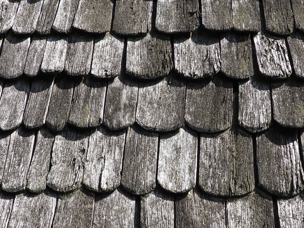 Roof shingles as a traditional rural roof covering. Tiled acute angled cross slab roofing piece material close-up. Wooden architecture of ancient craftsmen - carpenters. Natural background - Фото, зображення