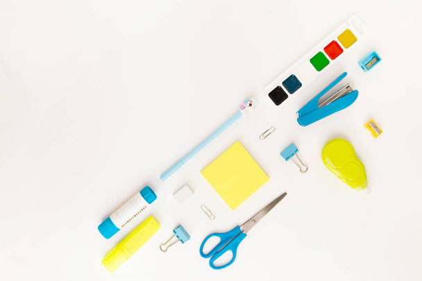 Top view of modern white, blue, yellow office desktop with school supplies and stationery on table around diagonal empty space for text. Back to school concept flat lay with mockup - Φωτογραφία, εικόνα