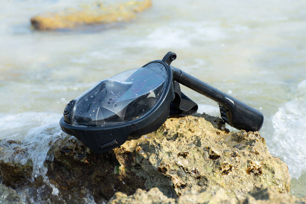 Полная маска для подводного плавания лежит на берегу моря, омытая волнами - Фото, изображение