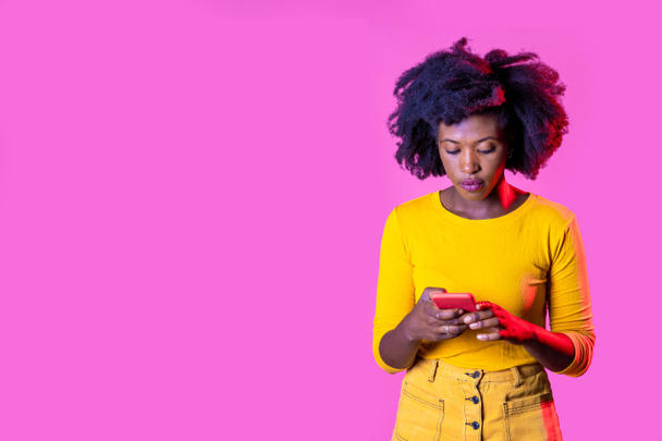 Isolé noir jeune femme en utilisant smartphone regarder la vidéo surf web sur fond de publicité copyspace - Photo, image