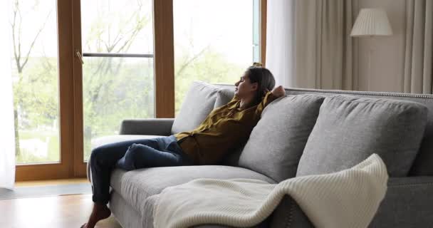 Young woman fall asleep on sofa in modern living room - Кадри, відео