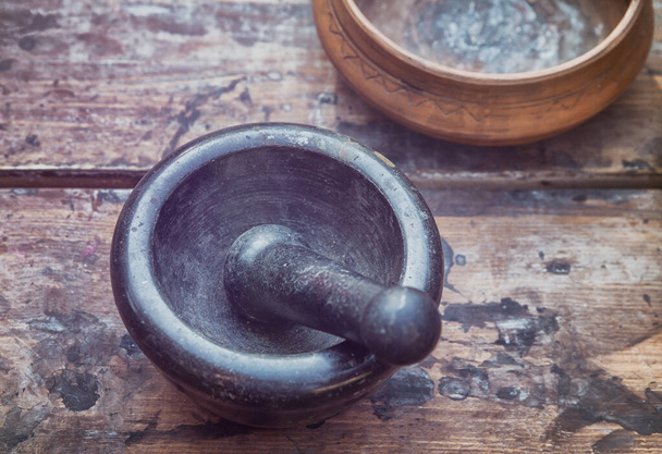 mortar & pestle black stone on a wooden table, traditional utensils for alchemy - Foto, Bild