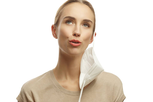 Женщина в медицинской маске висит на ухе изолированы на белом фоне - Фото, изображение