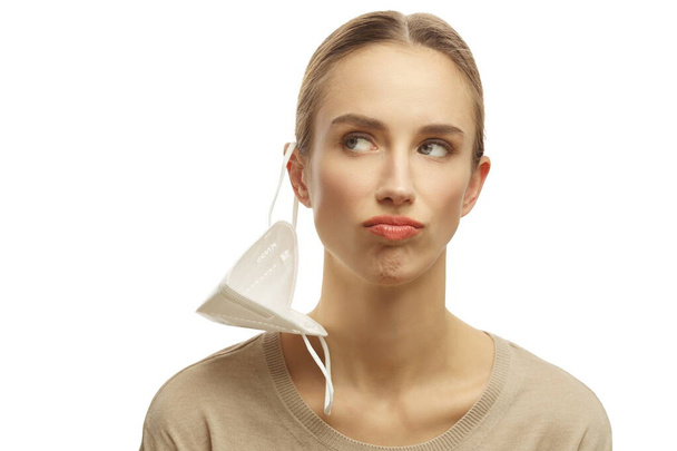 Portrait of frustrated woman wearing medical facemask looking sideways isolated over white background - 写真・画像