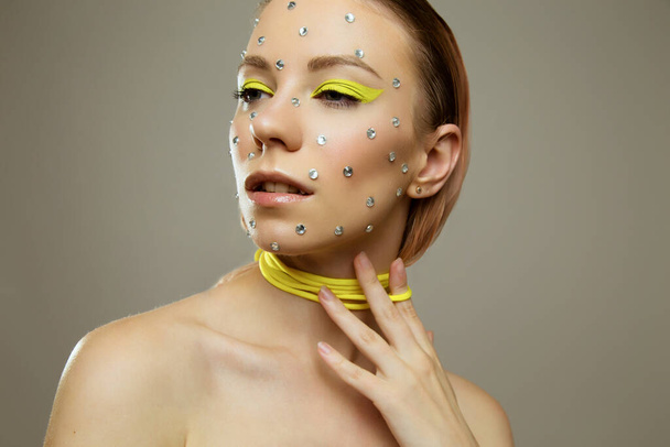 Studio portrait of beautiful girl with creative bright yellow makeup with rhinestones - Zdjęcie, obraz