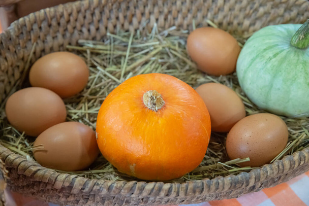 Orangenkürbis und Eier im Korbteller - Foto, Bild