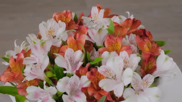 Ramo de flores de alstroemeria anaranjadas y blancas sobre superficie giratoria: primer plano - Metraje, vídeo