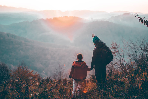 Father and daughter enjoying the sun and view in beautiful autumn forest in the sunset. Happy family concept. - Foto, imagen