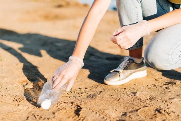 Junge Ehrenamtliche sammeln Müll, Plastikflaschen und Kaffeetassen, säubern Strand und Meer. Frau beim Müllsammeln. Umweltökologisches Verschmutzungskonzept. Tag der Erde - Foto, Bild