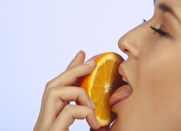 Young woman enjoying a slice of orange - Фото, зображення