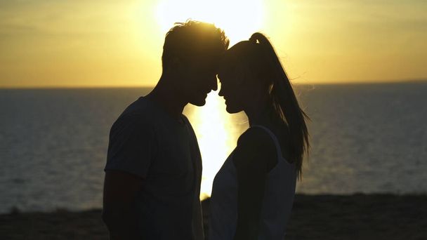 海の夕日の上に立つロマンチックなカップル - 写真・画像