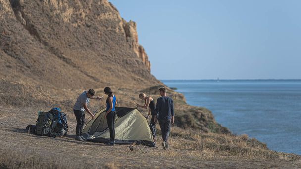 Los excursionistas con una tienda de campaña de pie en la montaña contra la vista al mar - Foto, Imagen
