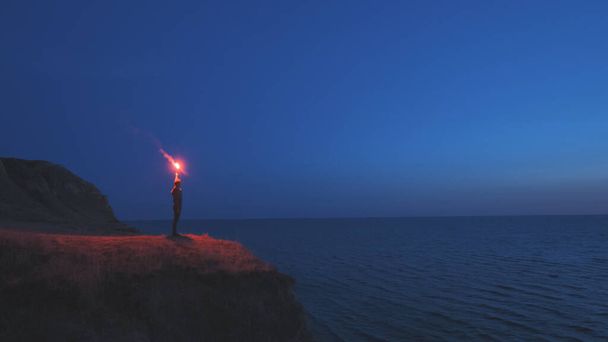 海の近くの山の頂上に火の棒を持った男 - 写真・画像