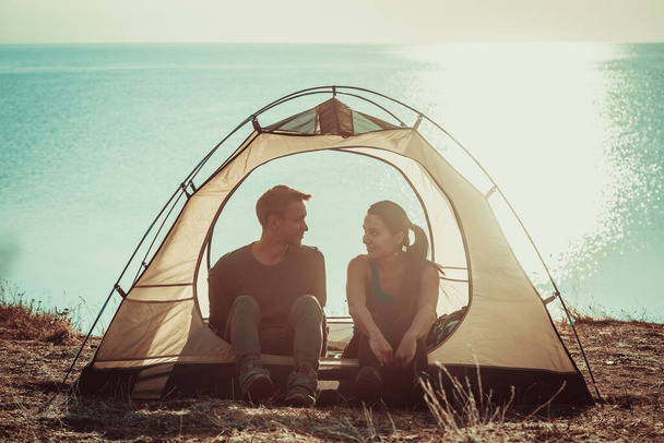 Kadın ve erkek, deniz kenarındaki kamp alanında eğleniyor. - Fotoğraf, Görsel