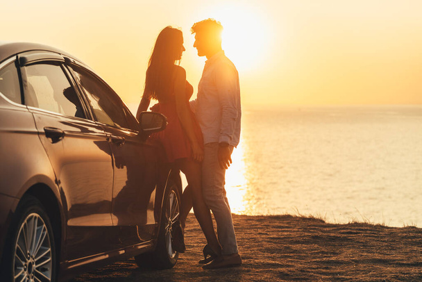 The beautiful couple standing near the car on the sea shore - 写真・画像