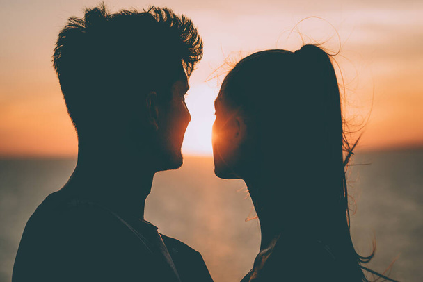 Το ρομαντικό ζευγάρι στέκεται κοντά στο όμορφο φόντο του ηλιοβασιλέματος - Φωτογραφία, εικόνα