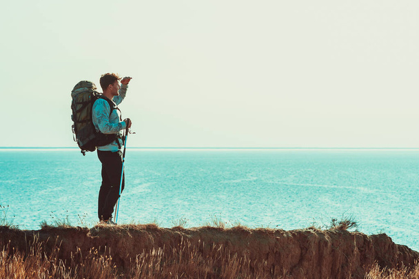 Cestovatel s batohem stojí na vrcholu hory nad mořem - Fotografie, Obrázek