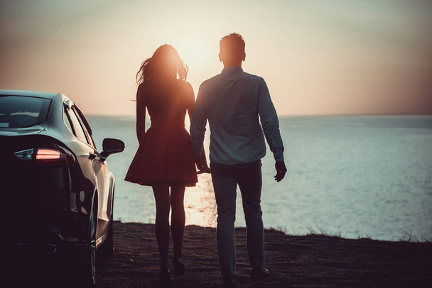 Muž a žena kráčející poblíž auta na mořském břehu - Fotografie, Obrázek