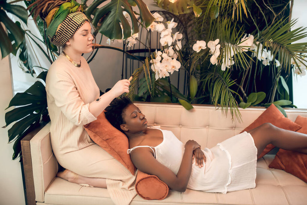 Caucasian woman sitting and reclining african american in spa - Foto, afbeelding