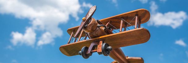A mão segura um avião de madeira no fundo da nuvem
 - Foto, Imagem