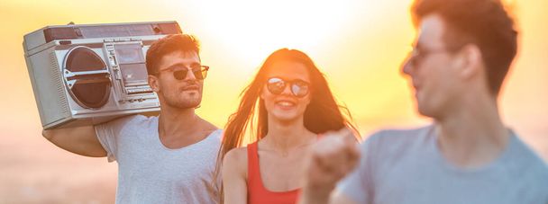 The three people with a boom box dancing on the sunset background - Photo, Image