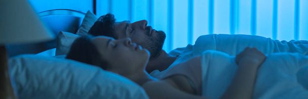La atractiva pareja durmiendo en la cama. tiempo de noche - Foto, imagen