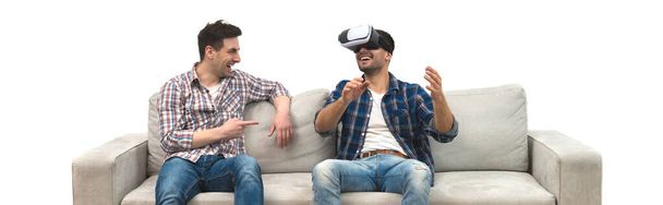 The two men with virtual glasses gesture on a sofa on a white wall background - Фото, зображення