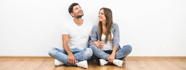 Der fröhliche Mann und die Frau sitzen an der leeren Wand - Foto, Bild
