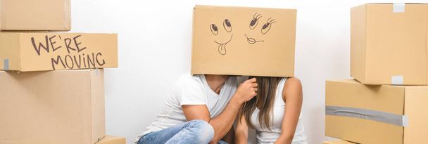 Мужчина и женщина сидят на полу с коробкой на голове - Фото, изображение