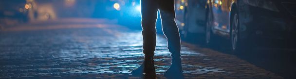 L'homme se tient sur la route de pierre. Bonsoir, la nuit. Téléobjectif tourné
 - Photo, image