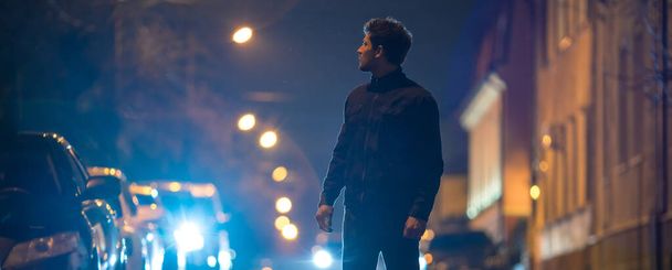 男は道路に立っている。夜の時間だ。望遠レンズショット - 写真・画像