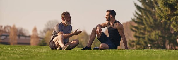 Vater und Sohn sitzen auf dem Gras und reden - Foto, Bild