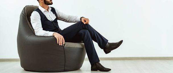 O empresário sentado em uma cadeira de saco no fundo da parede branca
 - Foto, Imagem