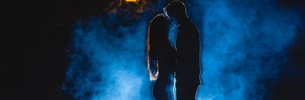 The man and woman kissing on the street on a blue smoke background. night time - Photo, Image