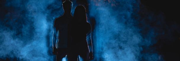Pariskunta seisoo pimeällä kujalla sinisellä savutaustalla. yöaika - Valokuva, kuva