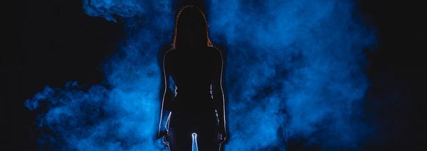 Силуэт женщины на улице на фоне синего дыма. ночь время - Фото, изображение