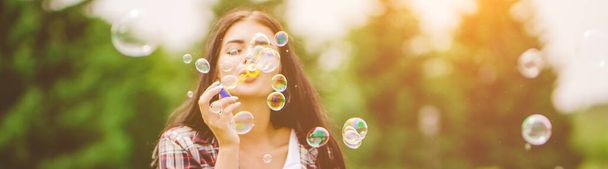 The happy woman blowing bubbles in the park - Fotoğraf, Görsel