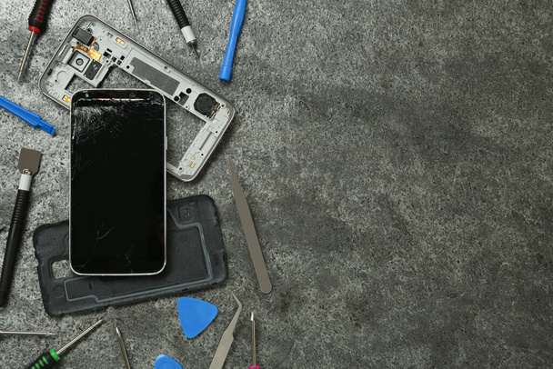 Parts of damaged smartphone and repair tool set on grey table, flat lay. Space for text - Фото, зображення