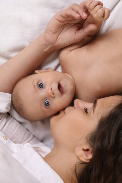 Young mother with her cute baby on bed, top view - Photo, Image