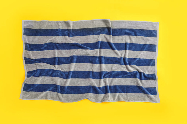 Crumpled striped beach towel on yellow background, top view - Foto, afbeelding