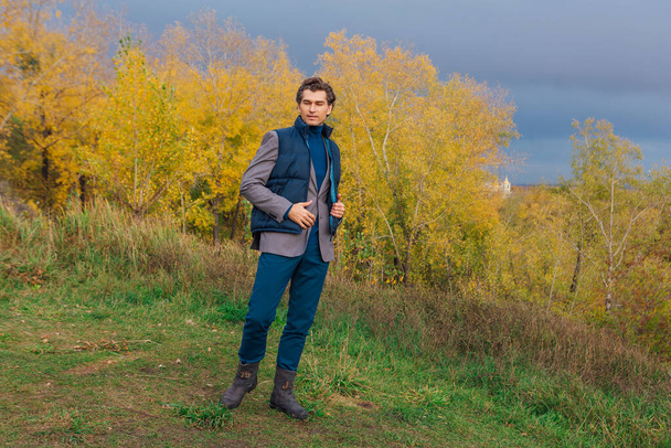Tall handsome man walking outdoor in yellow autumn forest on the hill before storm - Zdjęcie, obraz