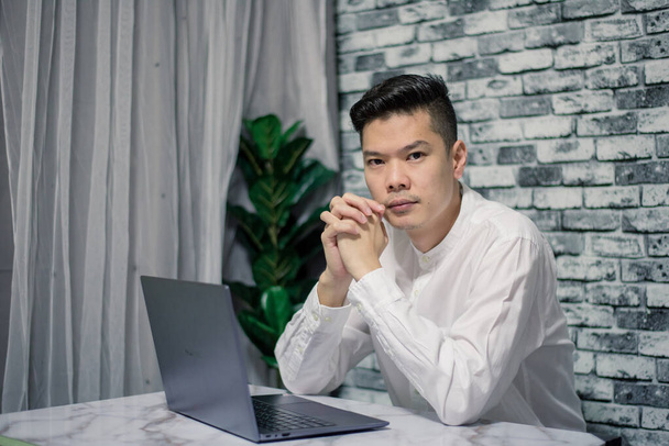 Portrait of young man businessman working  at  office with laptop on desk, looking at camera, smiling. - 写真・画像