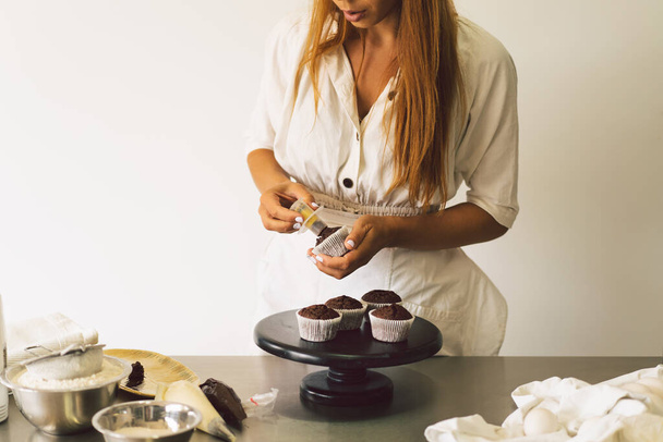 Confectioner girl is preparing a cupcakes. Concept ingredients for cooking flour products or dessert - Valokuva, kuva
