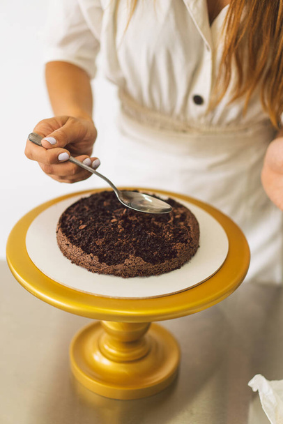 Η Εξομολογήτρια ετοιμάζει μπισκότο με λευκή κρέμα και σοκολάτα. Μαγείρεμα κέικ. - Φωτογραφία, εικόνα
