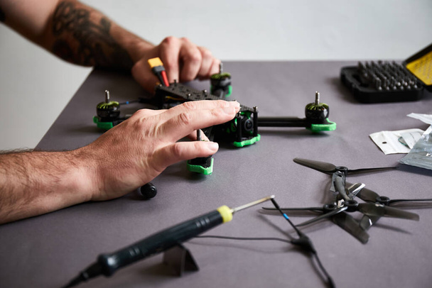 Close up of man's hands assembling a drone from parts, using tools, Preparing high-speed racing quadcopter for flight. Repair drone before training process. - Fotografie, Obrázek