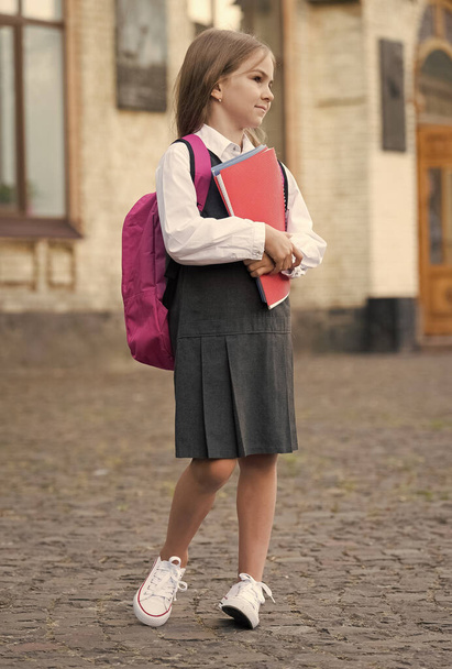 Small kid in formal uniform with back to school look carry bag holding books and supplies, college - Foto, Imagem