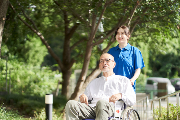 Жіночий доглядач, який підтримує літніх людей у інвалідних візках
 - Фото, зображення