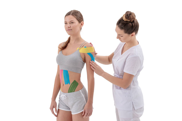 Physiotherapist applying kinesio tape on female patients shoulder - Fotó, kép