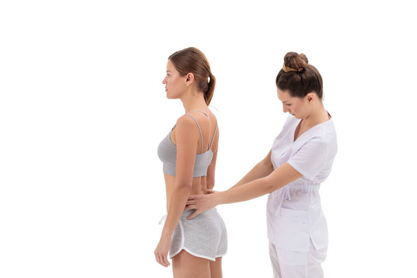 Physical therapist applying kinesio tape on female patients lower back. Kinesiology, physical therapy, rehabilitation concept. - Fotografie, Obrázek
