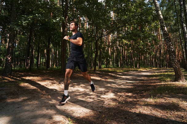 Happy young man running fast in wood - Foto, imagen